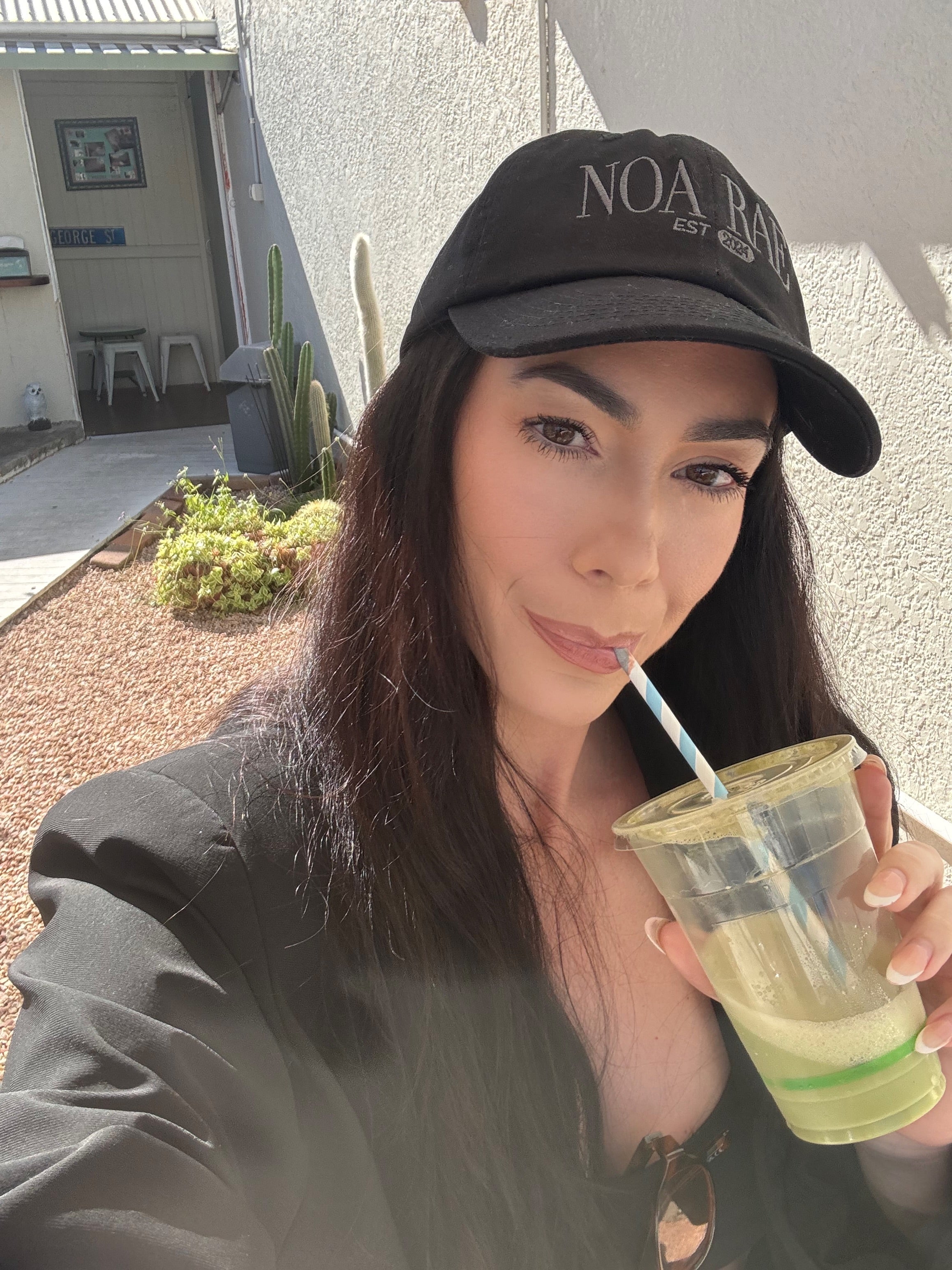 Woman drinking from a green cup with a straw outdoors