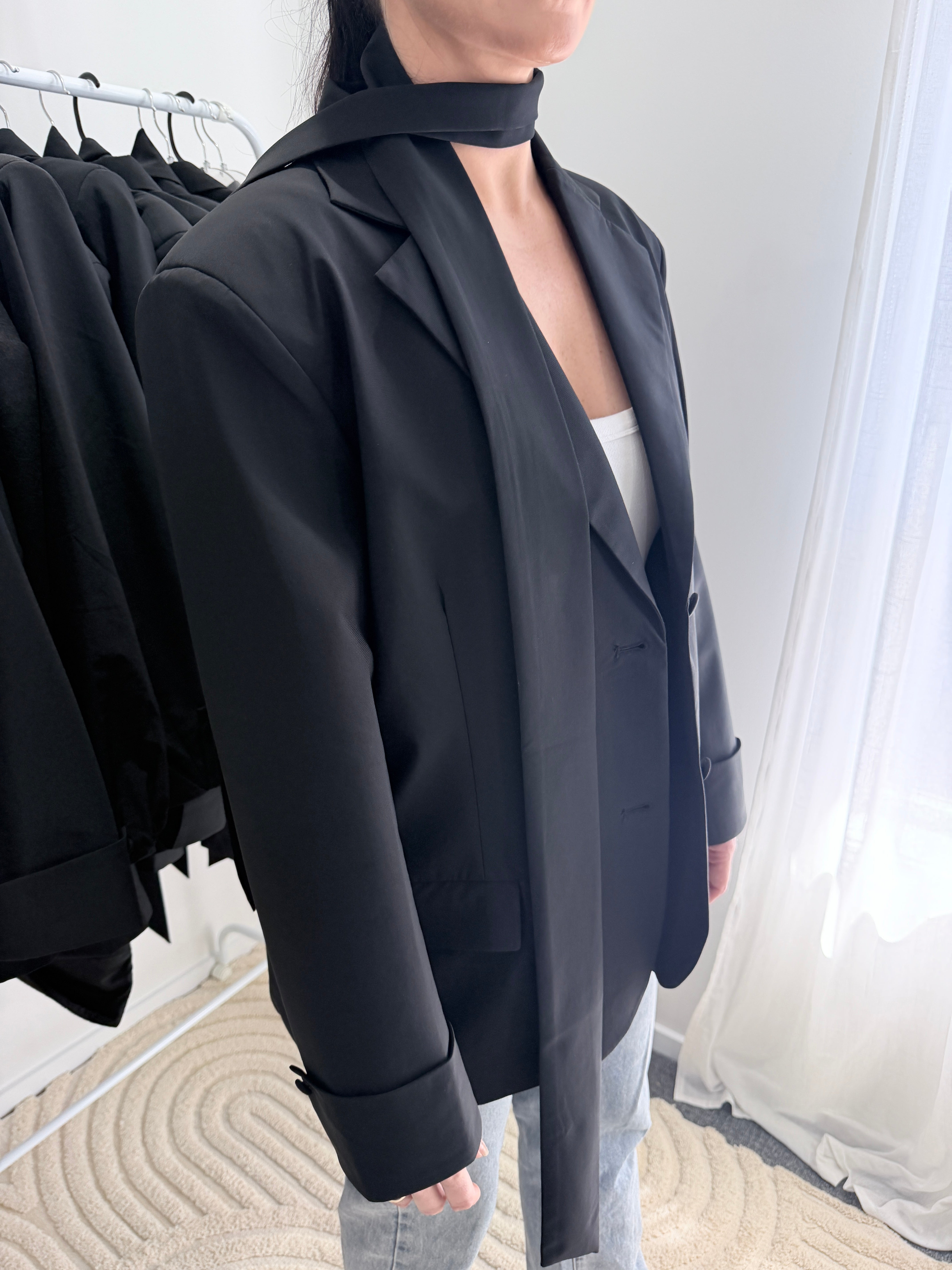 Person holding a black jacket with a blurred background