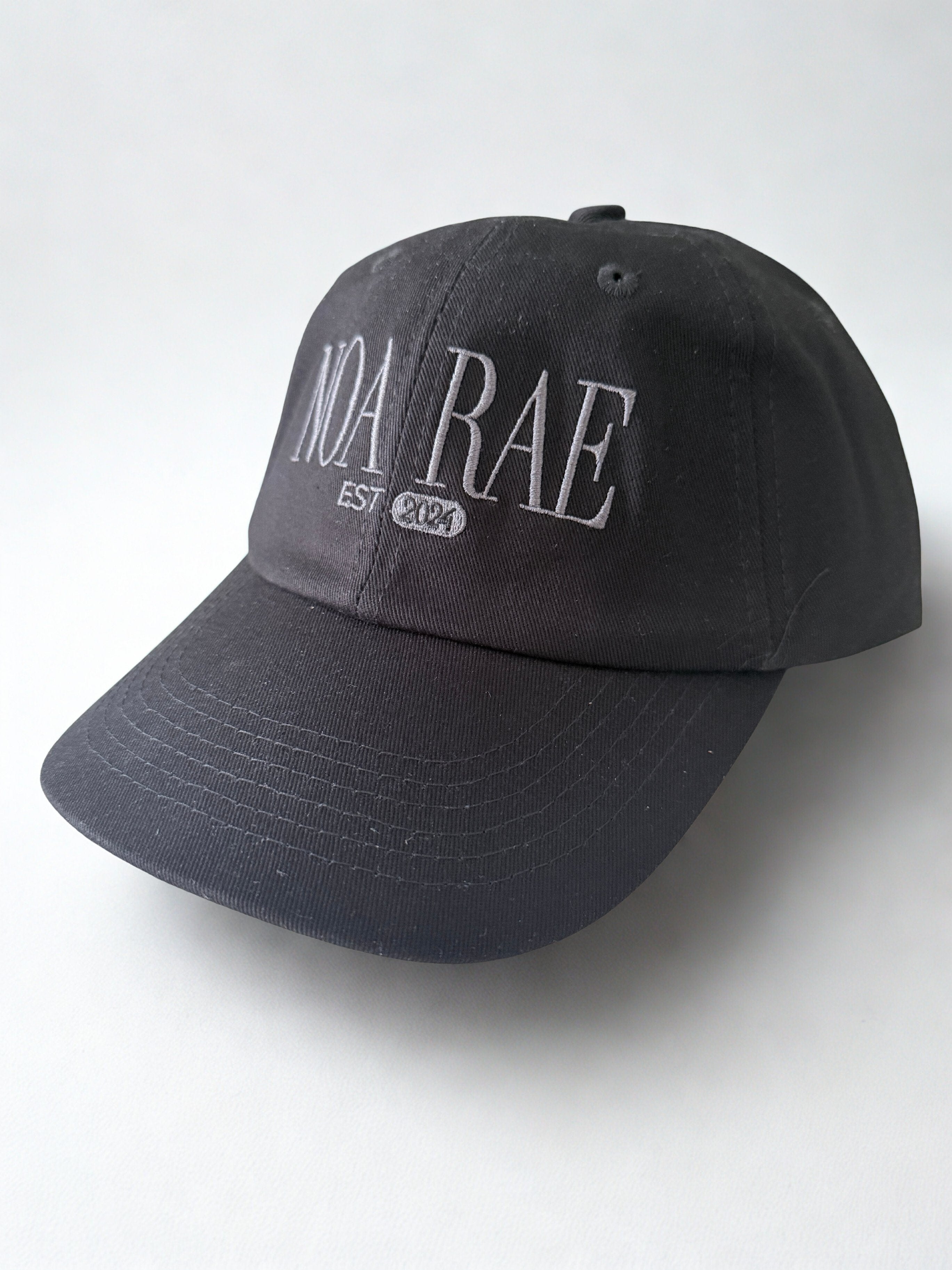 Black cap with 'NOA RAE' branding on a white background